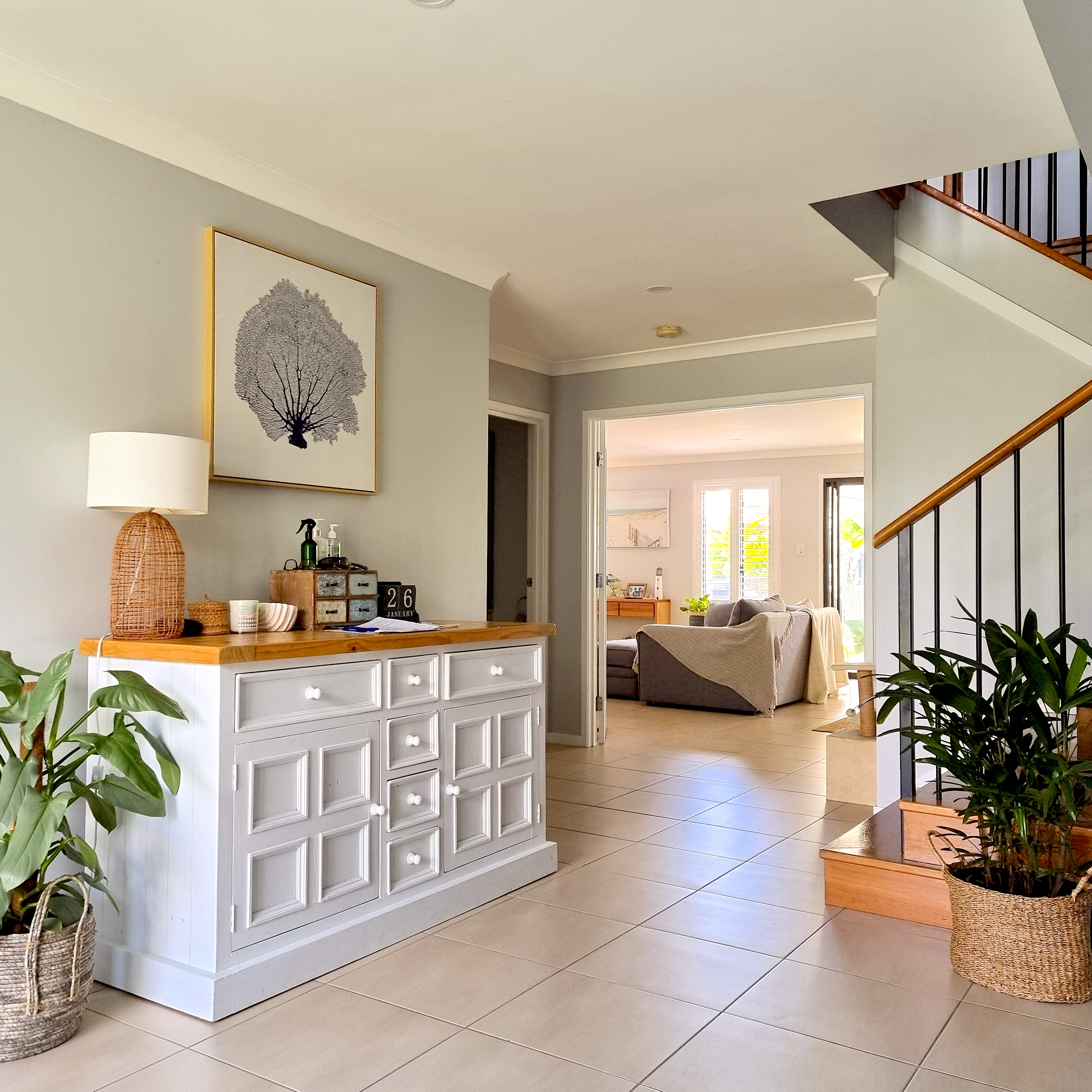 Living room with a white sideboard, lamp, and framed artwork and indoor plants.